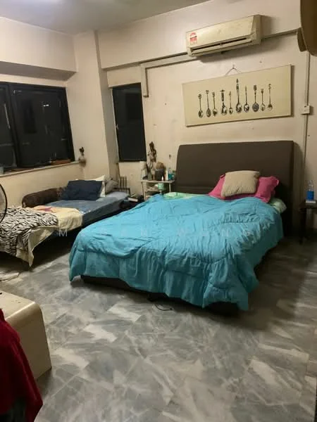Bedroom features: king-size bed with blue bedding, single bed with grey bedding, two bedside tables, wall-mounted air conditioning unit, large windows with black frames, marble tile flooring, decorative wall art, ceiling light fixture, wall with visible marks, fan on the floor.