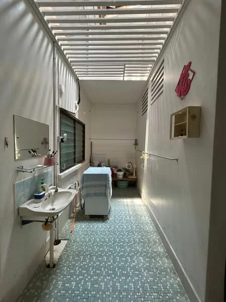 Laundry features: white painted walls, blue mosaic tile flooring, single-bowl sink, washing machine, window with horizontal slats, shelf for storage, light fixture, wall-mounted mirror.