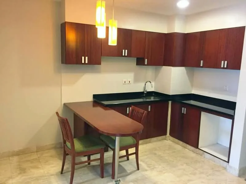 Kitchen features: dark wood cabinetry, black granite countertop, single-bowl stainless-steel sink, chrome pull-down faucet, two pendant lights, tile flooring, breakfast bar with two chairs, wall-mounted electrical outlets; style: modern.