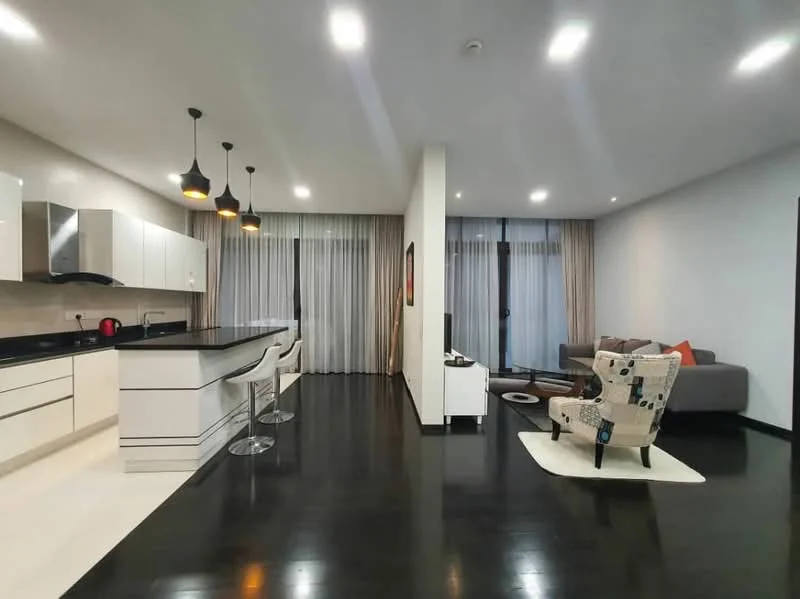 Living features: dark wood flooring, floor-to-ceiling windows, sheer curtains, grey fabric sofa, decorative cushions, coffee table, area rug, wall-mounted TV, entertainment unit, recessed LED downlights; style: modern. Kitchen features: white cabinetry, black countertop, stainless-steel sink, chrome pull-down faucet, built-in oven, freestanding range oven, 3 pendant lights, bar seating with stools; style: modern.