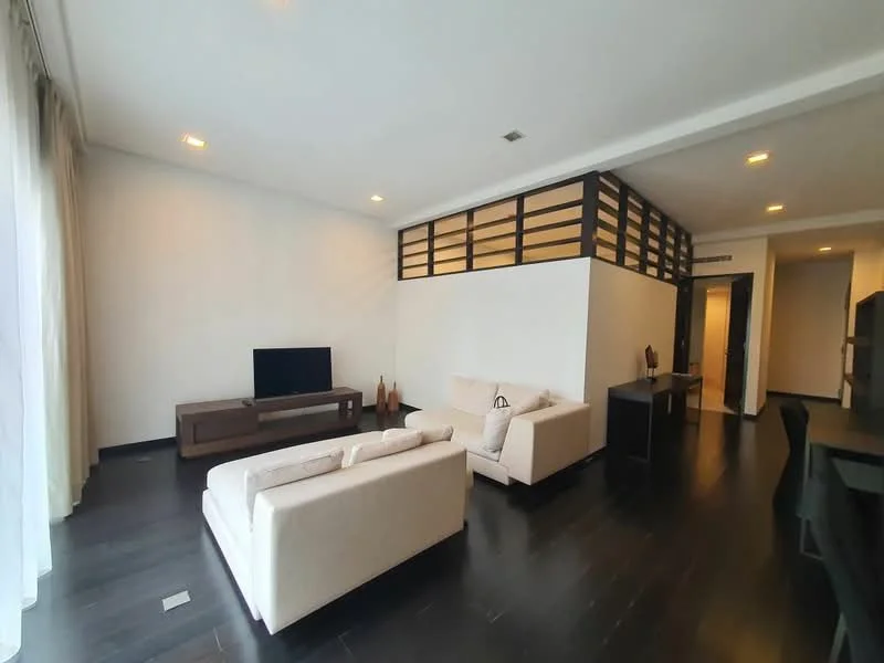 Living features: light-coloured fabric sofa, dark wooden coffee table, wall-mounted TV, dark wooden TV console, dark wooden flooring, white painted walls, recessed ceiling lights, large windows with sheer curtains, decorative vases, open layout to dining area, partition wall with wooden slats; style: modern.