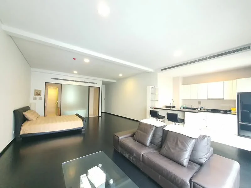 Living features: dark wood flooring, recessed downlights, sofa in brown leather, coffee table, wall-mounted TV, open layout to kitchen, floor-to-ceiling windows, neutral painted walls; style: modern. Bedroom features: queen-size bed, neutral bedding, wooden bed frame, built-in wardrobe, neutral painted walls; style: modern. Kitchen features: white cabinetry, black refrigerator, stainless-steel sink, chrome pull-down faucet, breakfast bar with stools, white countertop, built-in oven, ceramic tile backsplash; style: modern.