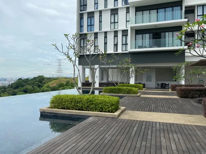 Exterior type: high-rise condominium; features: infinity pool, wooden deck, landscaped garden with shrubs, outdoor seating area, balconies on upper floors, surrounding greenery, city skyline view in background; style: modern.