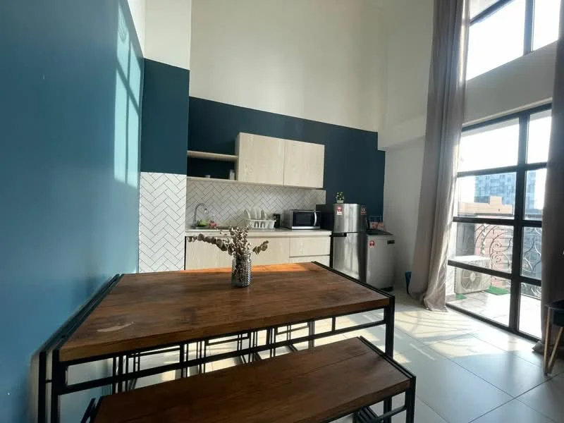 Kitchen features: blue accent wall, white herringbone tile backsplash, light wood cabinetry, stainless-steel fridge, microwave, kitchen countertop, dining table with wooden surface, metal dining benches, large windows with sheer curtains, floor tiles, decorative vase with dried flowers; style: modern; view: city.