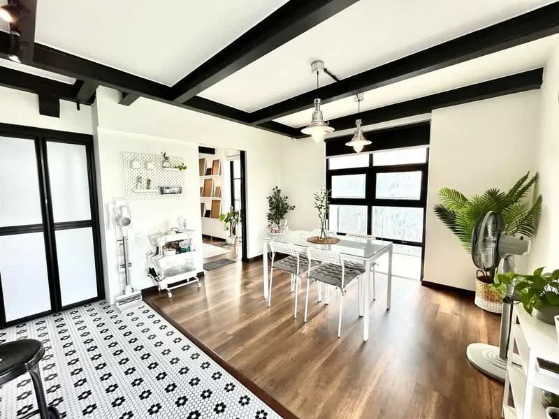 Dining features: wooden flooring, black and white patterned area rug, white dining table, 4 upholstered dining chairs, black ceiling beams, recessed downlights, 3 pendant lights, large windows with black frames, indoor plants, white shelving unit, decorative wall art, ceiling fan; style: modern; view: city. Room features: white painted walls, black sliding doors, open layout.