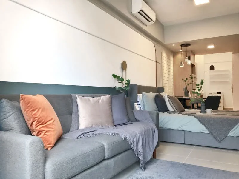 Living features: grey fabric sofa, orange throw pillow, light grey throw blanket, decorative cushions in various colors, wall-mounted air conditioning unit, recessed ceiling lights, pendant light fixture, wooden dining table, dining chairs, greenery in pots, textured wall paneling, neutral color scheme, tile flooring; style: modern.