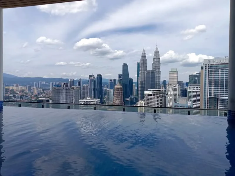 Exterior type: high-rise condominium; features: infinity pool, city skyline view, surrounded by urban landscape, glass railing, pool deck with loungers; style: modern.