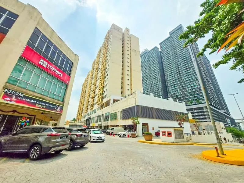 Exterior type: high-rise condominium; features: modern glass facade, multiple storeys, surrounded by urban landscape, open-air parking lot, driveway with interlocking pavers, commercial spaces at ground level, landscaped planters, adjacent to other high-rise buildings; style: modern.