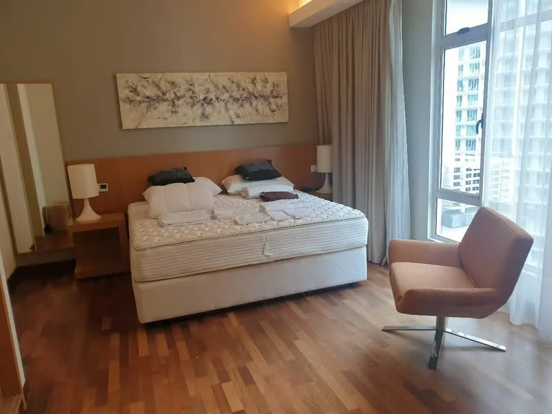 Bedroom features: king-size bed, upholstered headboard, wooden flooring, floor-to-ceiling windows, sheer curtains, 2 bedside lamps, decorative wall art, dressing table with mirror, armchair, built-in wardrobe; style: modern; view: city.