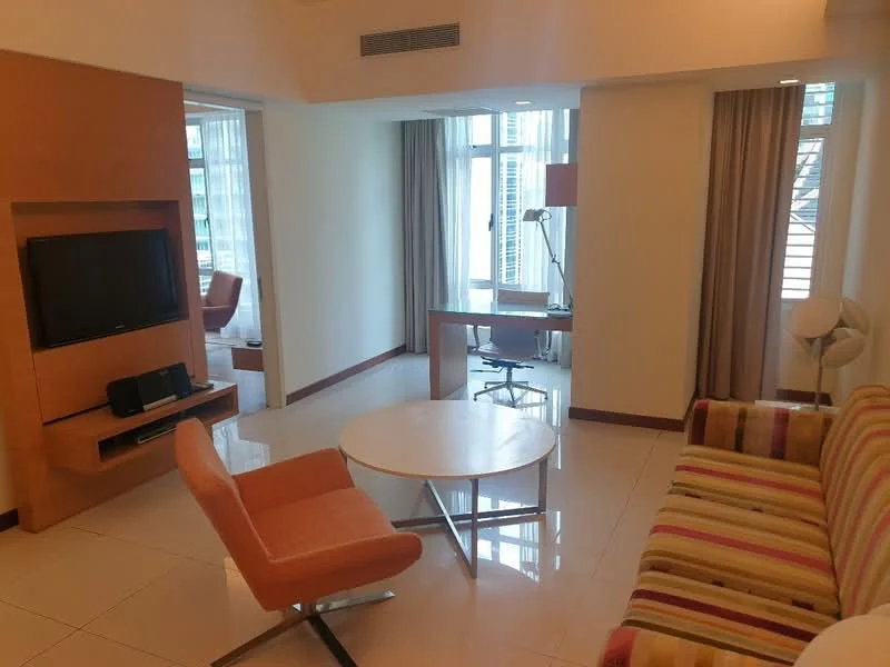 Living features: striped fabric sofa, orange accent chair, round coffee table, wall-mounted TV, wooden TV console, floor-to-ceiling windows, curtains, tile flooring, desk with chair, desk lamp; style: modern; view: city.