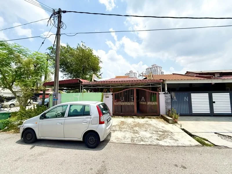 Exterior type: semi-detached house; features: red tiled roof, cream painted facade, metal gate, front porch with concrete flooring, single-storey, surrounded by greenery, visible car parked in driveway, power lines overhead; style: traditional.