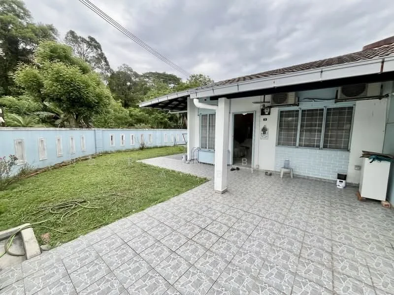 Exterior type: detached bungalow; features: paved patio area, manicured lawn, greenery surrounding the property, exterior wall with light blue paint, windows with metal grilles, air conditioning units visible, single-storey structure, gutter along the roof, garden hose on the ground; style: modern.