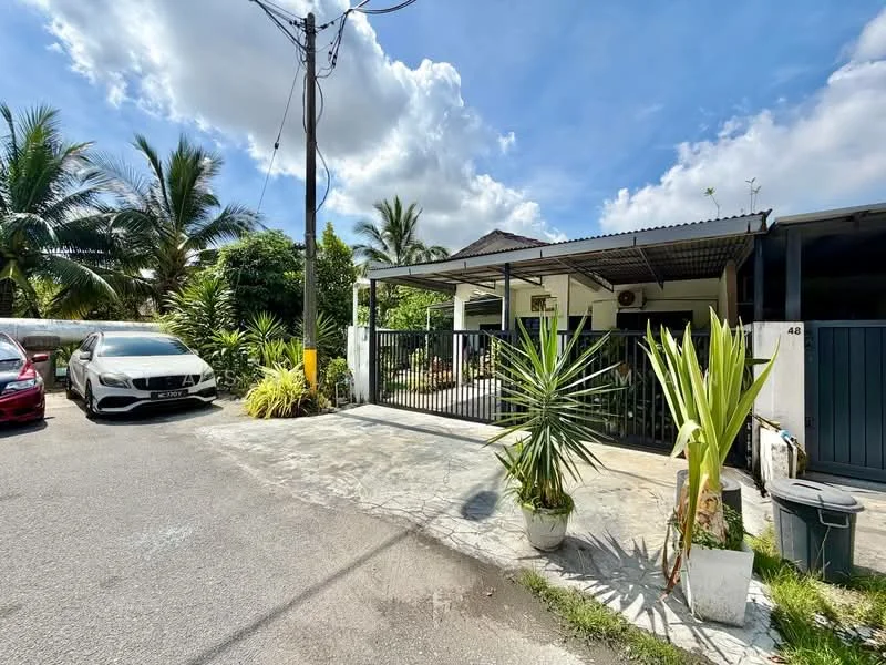 Exterior type: detached bungalow; features: single-storey, metal roof, white painted facade, fenced front yard, paved driveway, landscaped garden with tropical plants, car porch, visible palm trees, electricity pole, clear blue sky; style: tropical-modern.