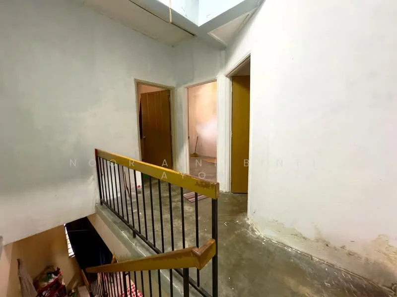 Room features: grey painted walls, concrete flooring, metal railing, two doorways, one open doorway, staircase, light source from above.
