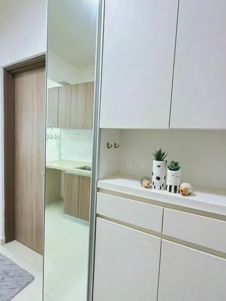 Room features: white cabinetry with gold trim, wooden cabinet doors, mirror panel, light-colored tiled flooring, decorative plants in ceramic pots, wall-mounted hooks, countertop with decorative items, open kitchen area visible in background; style: modern.