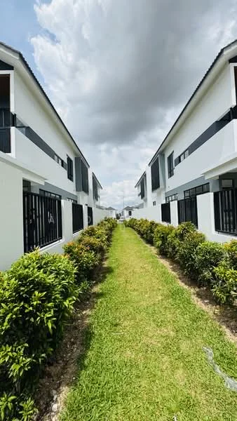 Exterior type: linked terrace house; features: white painted facade, black window grills, manicured lawn, pathway with gravel, two-storey buildings, landscaped hedges, cloudy sky, symmetrical layout; style: modern.