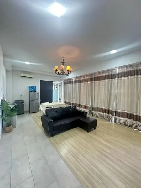 Living features: black leather sectional sofa, chandelier with multiple bulbs, recessed LED downlights, large windows with sheer curtains, light wood flooring, cream tiled flooring, wall-mounted air conditioning unit, potted plant, dining table with chairs, black cabinet, stainless-steel fridge; style: modern.