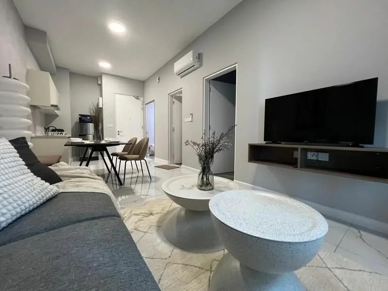 Living features: grey fabric sofa, round coffee table with textured surface, flat-screen TV on wall-mounted console, dining table with four upholstered chairs, white walls, recessed ceiling lights, air conditioning unit on wall, marble tile flooring, decorative vase with dried flowers; style: modern.