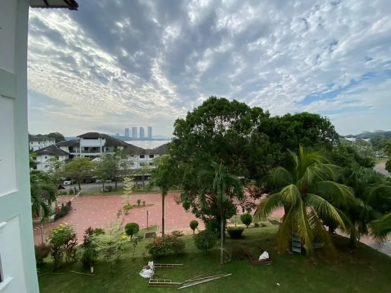 Exterior features: manicured lawn, mature trees, paved walkway, city skyline in background, surrounded by greenery, open space with parking area.