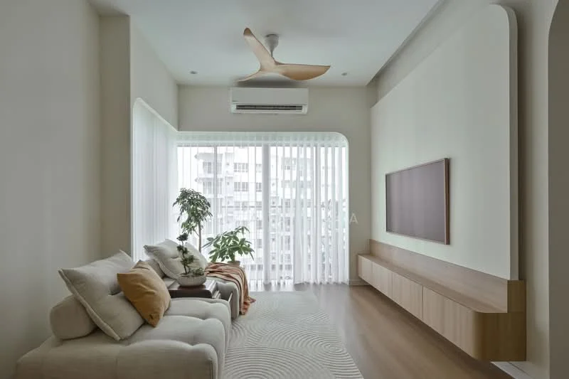 Living features: 3-seater fabric sofa in light beige, decorative cushions in orange and cream, wooden TV console, wall-mounted TV, area rug with circular pattern, floor-to-ceiling windows, sheer curtains, 1 wall-mounted split AC, 5-blade ceiling fan with light, indoor plant, light wood flooring, neutral painted walls; style: modern.