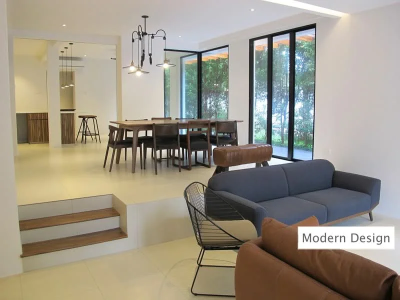 Living features: 3-seater fabric sofa in navy blue, black wire lounge chair, pendant lighting with multiple bulbs, white walls, light-colored tile flooring, large floor-to-ceiling windows, open layout to dining area, staircase leading to a lower level; style: modern; view: garden. Dining features: wooden dining table, 6 wooden dining chairs, pendant lighting above dining table, open layout to living area, large floor-to-ceiling windows; style: modern; view: garden.