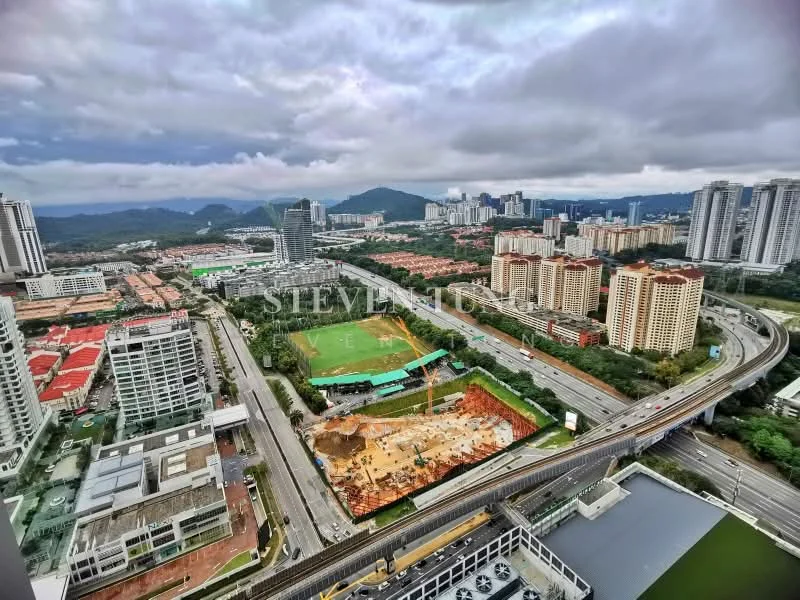Exterior type: high-rise condominium; features: city skyline view, surrounded by urban development, green field area, highway visible, construction site in foreground, mountainous backdrop, multiple high-rise buildings, mixed-use development, manicured landscaping, open space, road infrastructure; style: modern.