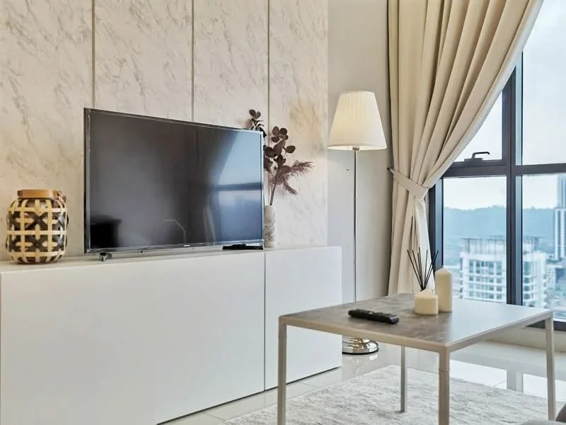 Living features: white TV console, flat-screen TV, decorative vase, floor lamp with shade, coffee table with marble top, area rug, curtains, wall with marble texture, city view through window; style: modern; view: city.