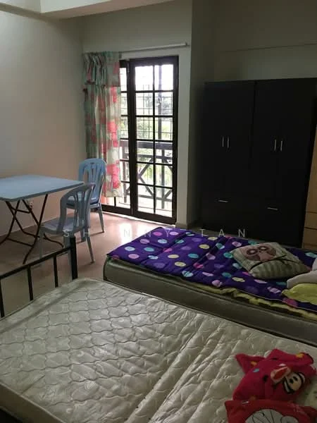 Bedroom features: two single beds with mattresses, purple patterned bedspread, wooden wardrobe in dark finish, light-colored walls, large window with black metal grille, curtains with colorful pattern, folding table, plastic chairs, laminate flooring.