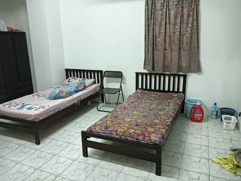 Bedroom features: two single beds with wooden frames, bedding with colorful patterns, curtains in a light brown color, tiled flooring in white, wooden wardrobe, plastic laundry basket, plastic storage container, folding chair.