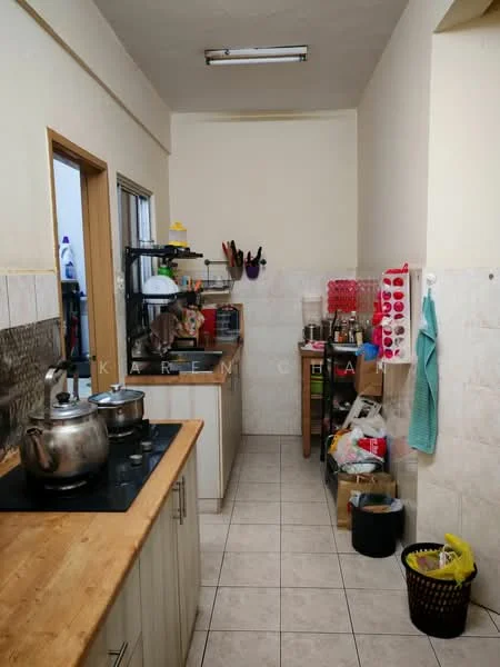 Kitchen features: wooden countertop, stainless-steel sink, chrome pull-down faucet, white cabinetry, ceramic tile flooring, wall-mounted shelves, window with metal frame, various kitchen appliances, pots and pans on stove, plastic storage containers, cleaning supplies, trash bin.