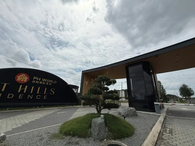 Exterior type: main entrance gate; features: large entrance sign with 'PH World' and 'Hills Residence', paved driveway, landscaped area with decorative stones, small ornamental tree, modern architectural design, overhang roof, visible security booth, surrounding greenery; style: modern.