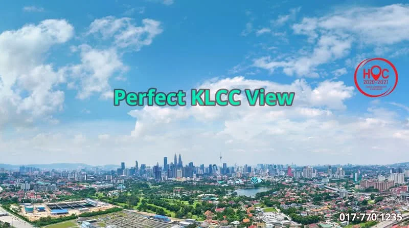 Exterior type: high-rise condominium; features: panoramic city skyline view, visible Petronas Twin Towers, lush green landscaping in foreground, urban residential area, clear blue sky, well-maintained roads, mixed-use development, surrounding greenery; style: modern.
