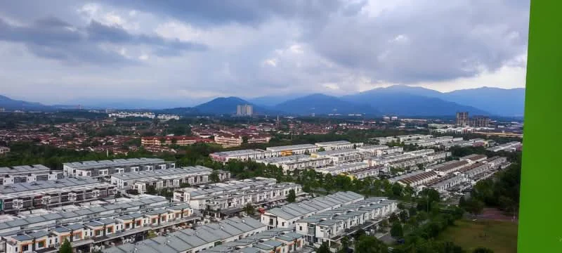 Exterior type: linked terrace house; features: multiple rows of linked terrace houses, green landscaping with trees, mountain view in background, urban residential area, manicured lawns, paved walkways, surrounding greenery, cloudy sky; style: modern.