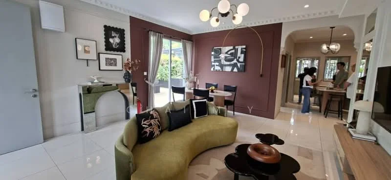 Living features: curved green fabric sofa, round wooden coffee table, black and white artwork on wall, decorative wall mirror, white walls with crown moulding, large windows with sheer curtains, recessed ceiling lights, pendant light fixture, polished marble flooring, area rug with geometric pattern; style: modern; view: garden. Dining features: wooden dining table, black dining chairs, decorative vase on table, wall-mounted TV, open layout to living area; style: modern; view: garden.