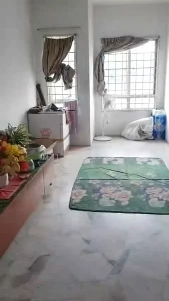 Room features: white painted walls, marble flooring, two windows with grid pattern, curtains on windows, green area rug with floral pattern, ceiling fan, wooden cabinet, refrigerator, plastic bags, decorative flowers.