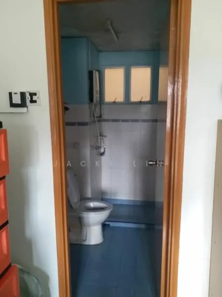 Bathroom features: white toilet, shower with handheld shower head, blue tiled flooring, light blue painted walls, white tiles on lower wall, window with frosted glass, wall-mounted mirror, wall-mounted shower faucet.