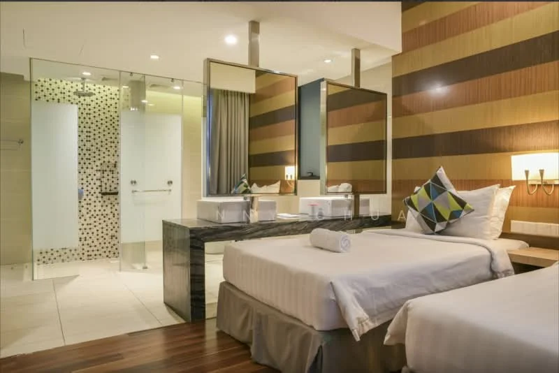 Bedroom features: two single beds with white bedding, decorative throw pillows, wooden flooring, striped accent wall in brown and cream, large mirror above the dresser, black marble dresser, glass shower enclosure, white tiled bathroom wall, grey curtains, wall-mounted bedside lamps, towel rolled on the bed; style: modern.