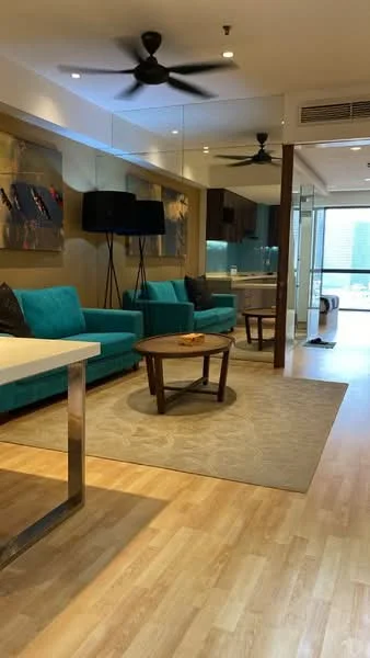 Living features: 3-seater fabric sofa in turquoise, 2-seater fabric sofa in turquoise, round wooden coffee table, area rug with geometric pattern, ceiling fan with light, wall-mounted TV, glass sliding door, floor-to-ceiling windows, decorative wall art, laminate flooring, recessed lighting, open layout, built-in cabinetry, natural light from windows; style: modern; view: city.