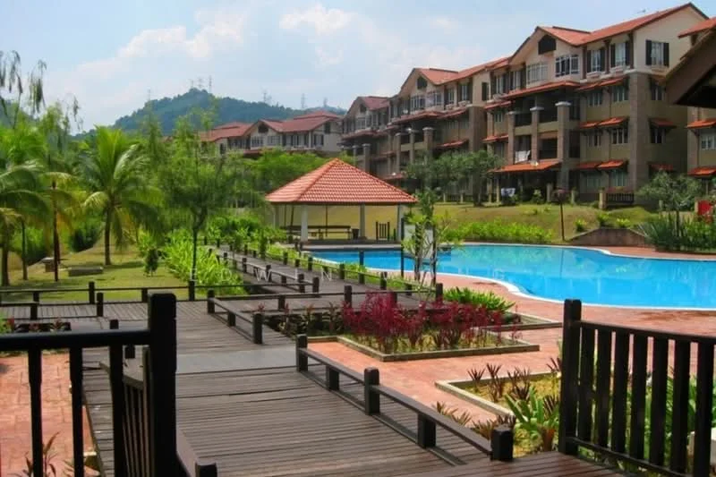 Exterior type: low-rise apartment block; features: swimming pool, pool deck with loungers, landscaped garden, manicured lawn, palm trees, tropical landscaping, gazebo with tiled roof, wooden walkway, multi-storey buildings, red tiled roof, green hillside in background, sunny weather; style: tropical-modern.