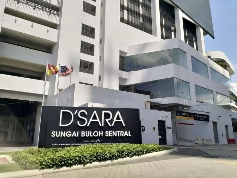 Exterior type: low-rise apartment block; features: white painted facade, glass windows, prominent signage, landscaped greenery, multiple flags displayed, parking entrance, modern architectural design; style: contemporary.