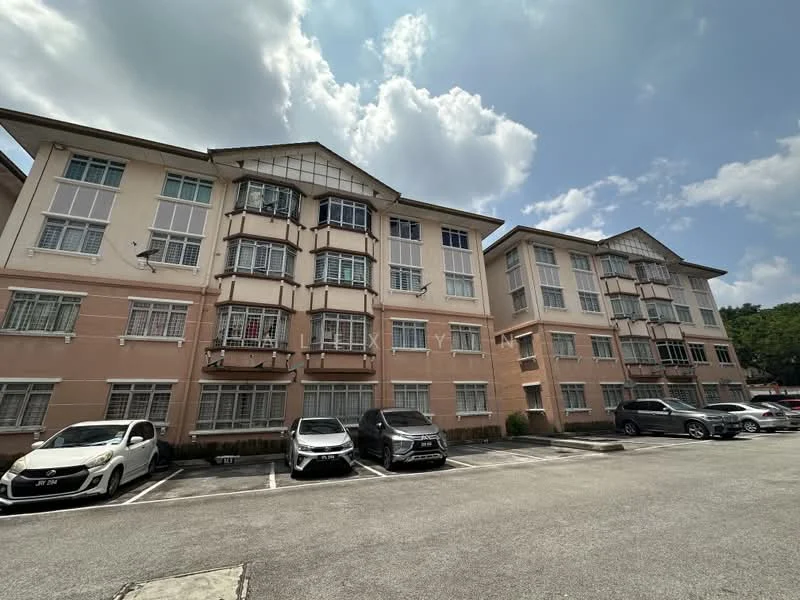 Exterior type: low-rise apartment block; features: pink painted facade, multiple windows with grills, flat roof, approximately 3-storey, parking lot with multiple vehicles, surrounded by greenery; style: traditional.