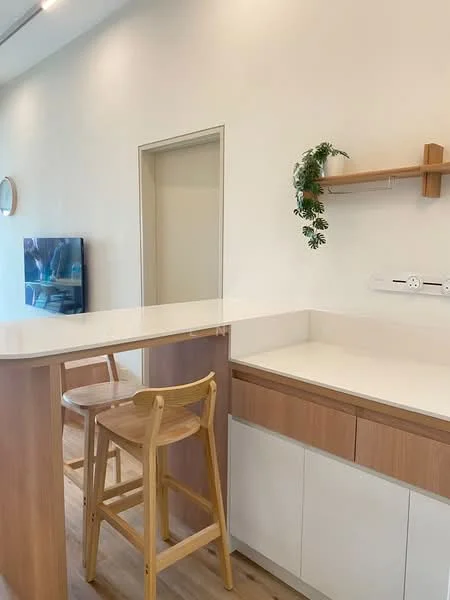 Kitchen features: white painted walls, light wood cabinetry, white countertop, bar counter with two wooden stools, open shelving, wall-mounted power outlet, decorative plant on shelf, TV mounted on wall; style: modern.