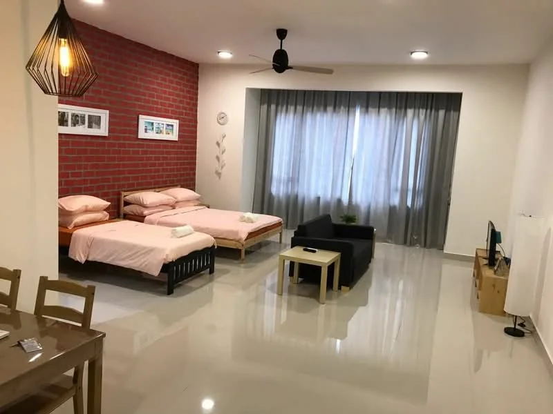 Room features: two single beds with pink bedding, black wooden bed frame, grey accent wall with exposed brick, white painted walls, polished tile flooring, ceiling fan with light, large window with sheer curtains, black sofa, light wood coffee table, TV console, decorative wall art, dining table with four chairs; style: modern.