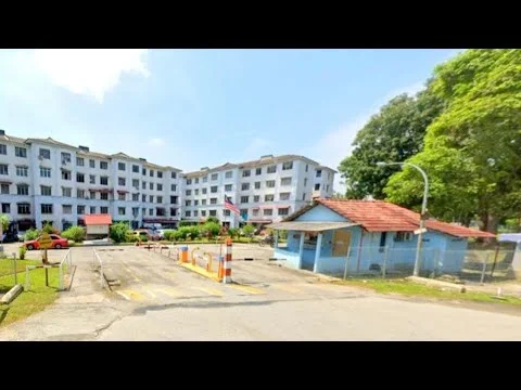 Exterior type: low-rise apartment block; features: white painted facade, red tiled roof, landscaped garden, security guard house, parking lot, surrounded by mature trees, multiple storeys, entrance with gate, flagpole with flag, driveway with interlocking pavers; style: traditional.