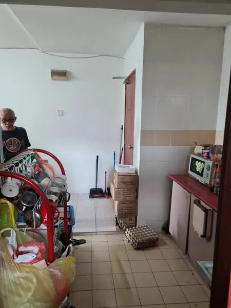 Room features: tile flooring, white painted walls, microwave, stacked boxes, shelves with kitchenware, broom, eggs in carton, cleaning supplies, door leading to another room.