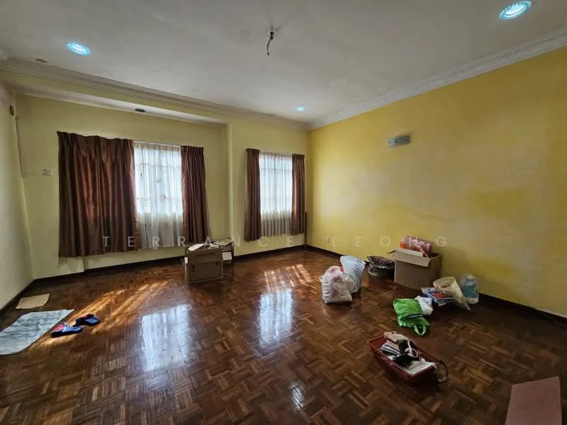 Living features: yellow painted walls, wood parquet flooring, two large windows with sheer curtains, brown curtains, ceiling with recessed lighting, boxes and bags on the floor, no visible furniture.