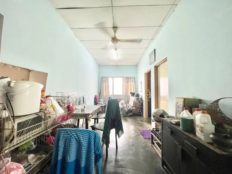 Room features: light blue painted walls, concrete flooring, ceiling fan, window with curtains, dining table, chairs, shelves with various items, storage cabinets, purple area rug, clothes hanging on a chair.