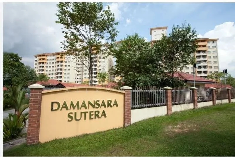 Exterior type: low-rise apartment block; features: brick facade, green landscaping, manicured lawn, mature trees, fenced perimeter, signage with name 'Damansara Sutera', multiple storeys, residential complex, adjacent road; style: modern.