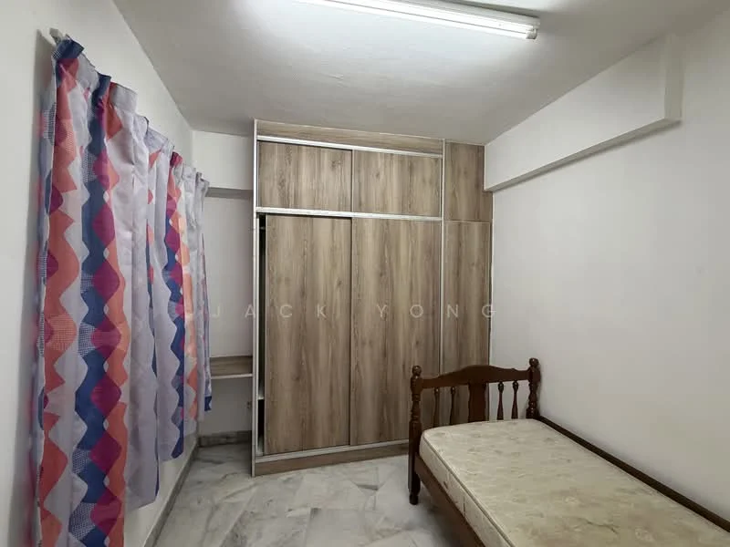 Bedroom features: single bed, wooden bed frame, built-in wardrobe with sliding doors, light-colored wood finish on wardrobe, white painted walls, marble flooring, curtains with geometric pattern, fluorescent ceiling light.