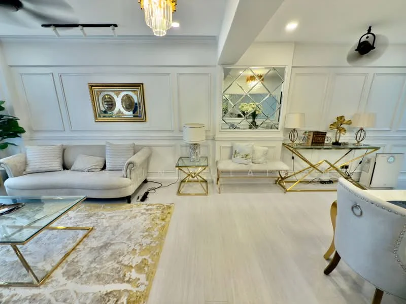Living features: light grey fabric 3-seater sofa, cream fabric 2-seater sofa, gold metal coffee table with glass top, gold metal console table, decorative mirror with diamond pattern, framed artwork, area rug with geometric pattern, white painted walls with wainscoting, recessed downlights, ceiling fan, indoor plants; style: modern.